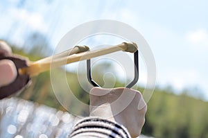 Young Boy Aiming Sling Shot Over Lake