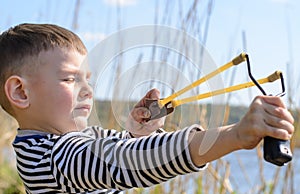 Young Boy Aiming Sling Shot Over Lake