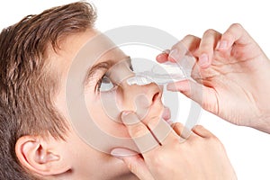 Young boy applying eye drop. On white background