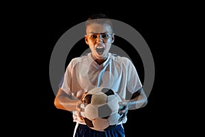 Young boy as a soccer or football player on dark studio background