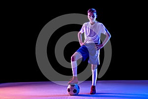 Young boy as a soccer or football player on dark studio background