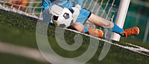 Young boy as a soccer goalie catching the ball during a soccer match. Football goalkeeper in jersey shirt