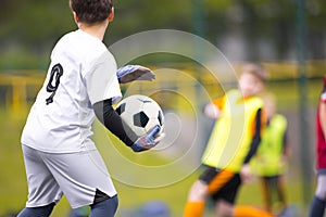 Young boy as a soccer goalie holding the ball in one hand ready to start a game. Football goalkeeper in jersey shirt