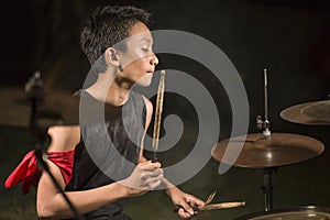 Young boy as talented rock band drummer . Handsome and cool Asian American teenager playing drum kit on stage performing night