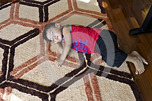 Young boy asleep on a colorful mat on the floor