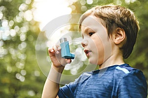 Young boy with asthma pump in the forest photo