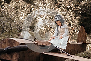 A young boy aviator on a homemade airplane in a natural landscape with a geographical map in his hands. The authentic