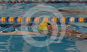 Young Boy in back stroke swim competition breaking surface of pool in water bubble