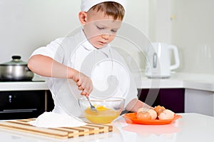 Young boy baking whipping eggs