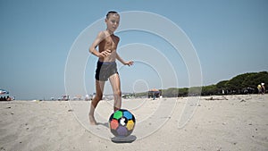 Young boy at the beach plays football ball