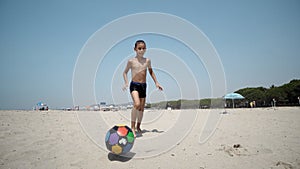 Young boy at the beach plays with a soccer