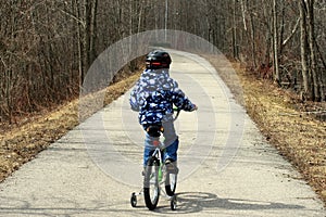 Young Boy on Bicycle with Training Wheels Learning to Ride Bike.