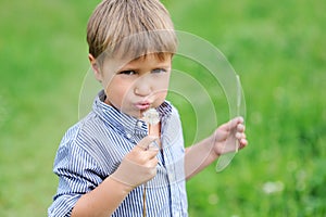 Young boy blowing dandelion