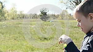 Young boy blowing soap bubbles in the clearing. Children`s entertainment, outdoor recreation