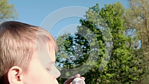 Young boy blowing soap bubbles in the clearing. Children`s entertainment, outdoor recreation