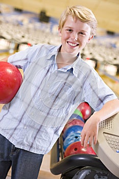 Young boy in bowling alley holding ball