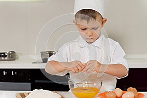 Young boy breaking fresh eggs into a bowl