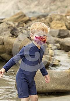 Young boy in a bright face mask playing in tidepools