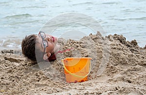 Young boy buried in the sand