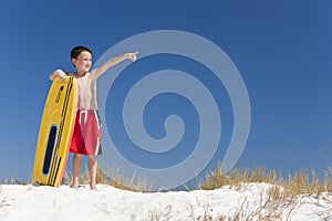 Young Boy Child on A Beach with Surfboard Pointing