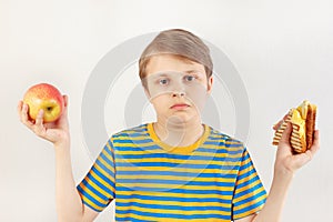 Young boy chooses between fastfood and fresh apple on white background