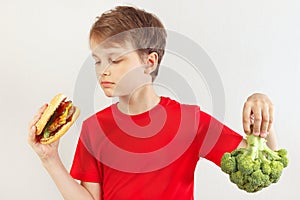 Young boy chooses between fastfood and vegetable on white background
