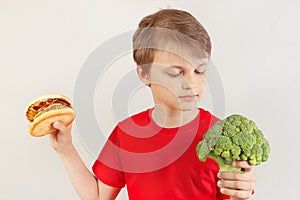 Young boy chooses between hamburger and vegetable on white background
