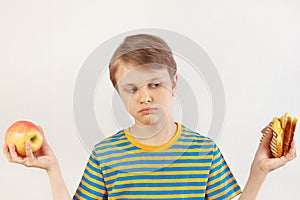 Young boy chooses between sandwich and healthy diet on white background