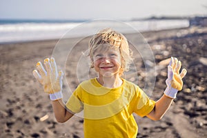 Young boy cleaning up the beach. Natural education of children