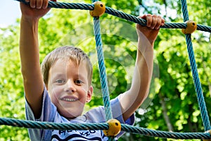 Young boy climbing rope on kid playground