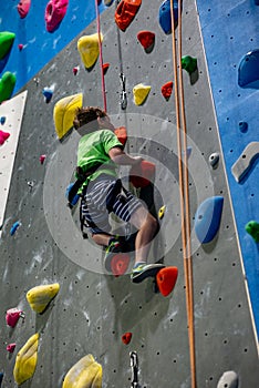 Young boy climbing up on practice wall in indoor rock gym