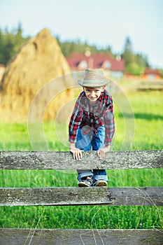 Young boy climbs over wooden fence look straight, close up