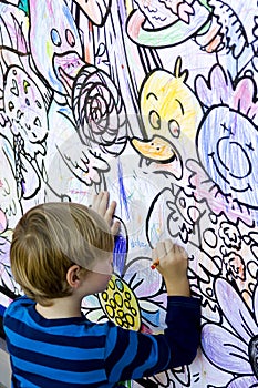 Young boy coloring a wall.