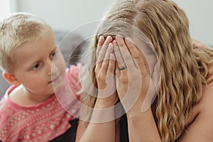 Young boy concerned for his mother and leaning into her comforting her as she cries photo