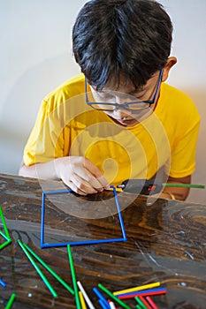 A young boy is constructing colorful plastic sticks with glue gun. fun with building geometric figures and learning mathematics at