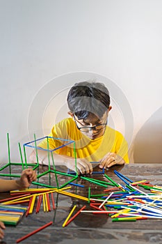 A young boy is constructing colorful plastic sticks with glue gun. fun with building geometric figures and learning mathematics at