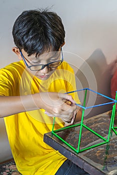 A young boy is constructing colorful plastic sticks with glue gun. fun with building geometric figures and learning mathematics at