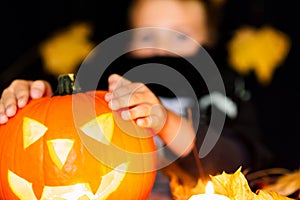 Young boy in costume dressed as a halloween cosplay of scary dacula holding a jack`o pumpkin lantern