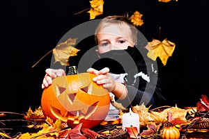 Young boy in costume dressed as a halloween cosplay of scary dacula holding a jack`o pumpkin lantern