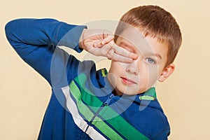 Young boy covering his eye.