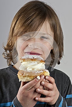 Young boy with a cream bun with almond paste