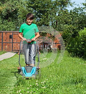 Young boy cutting the grass with a lawn mower
