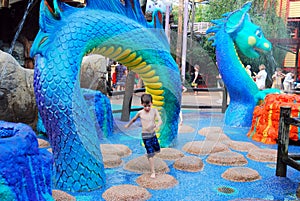 A young boy dances on the stones at a waterpark