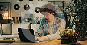 A young boy with dark hair is looking at his laptop, a credit card lying next to it. The man is pleased that after many