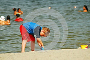 A young boy digs at the beach