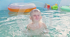 A young boy dives into an outdoor pool in the backyard during a sunny summer day