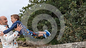 A young boy diving from a rock into his father's arms