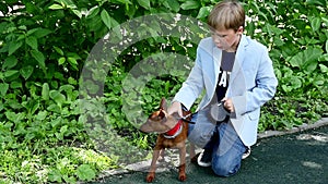 Young boy with dog in green park background slow motion.