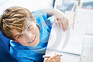 Young boy doing his homework at home. School kid learning.