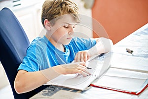 Young boy doing his homework at home. School kid learning.